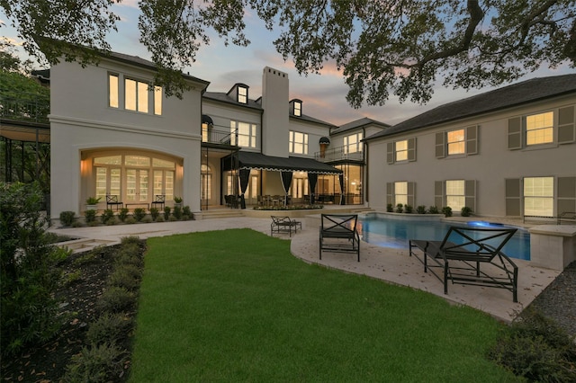 back of property featuring a yard, stucco siding, an outdoor pool, and a patio