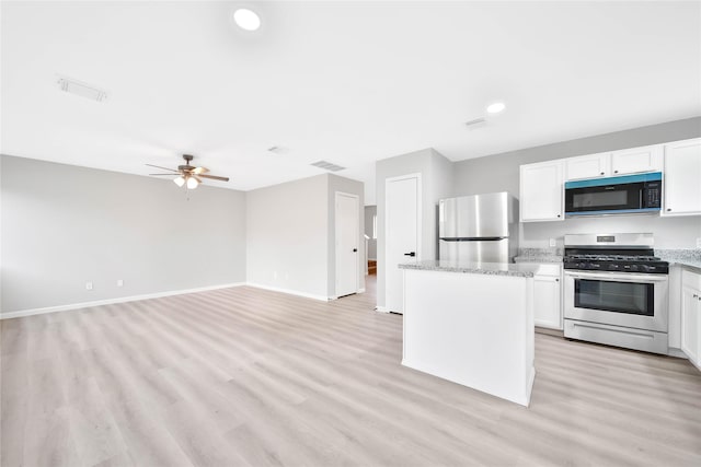 kitchen with white cabinetry, stainless steel appliances, light stone countertops, and a kitchen island