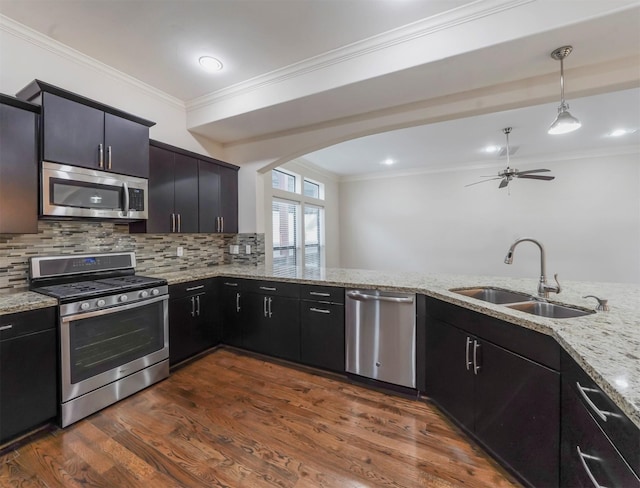 kitchen featuring pendant lighting, sink, appliances with stainless steel finishes, ornamental molding, and kitchen peninsula