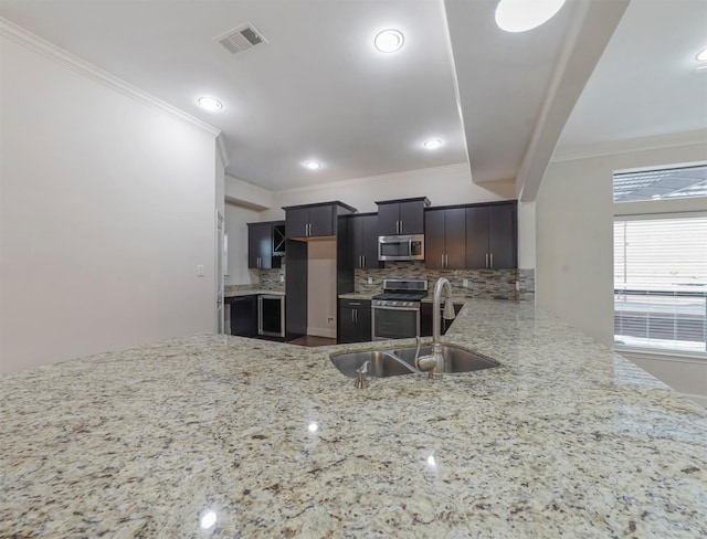 kitchen featuring appliances with stainless steel finishes, sink, backsplash, ornamental molding, and dark brown cabinetry