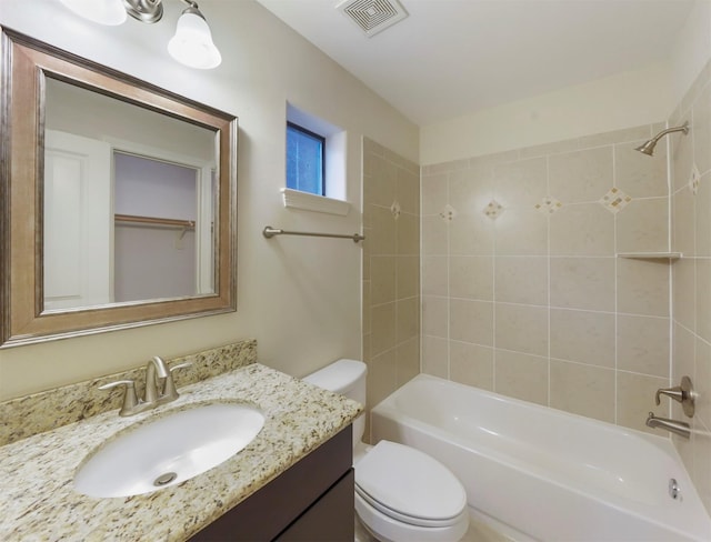 full bathroom with vanity, tiled shower / bath combo, and toilet