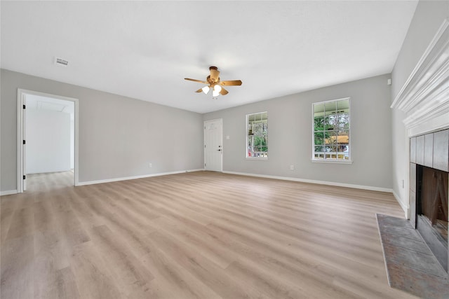 unfurnished living room featuring ceiling fan, a tiled fireplace, and light hardwood / wood-style flooring