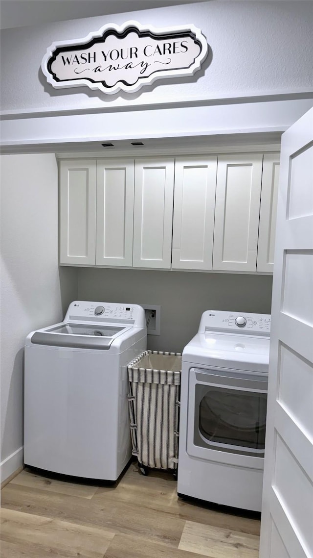 laundry room with cabinets, washer and clothes dryer, and light hardwood / wood-style flooring