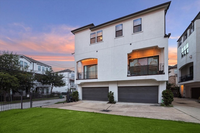 view of front of property featuring a garage, a balcony, and a lawn