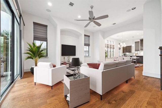 living room with ceiling fan with notable chandelier and light hardwood / wood-style floors