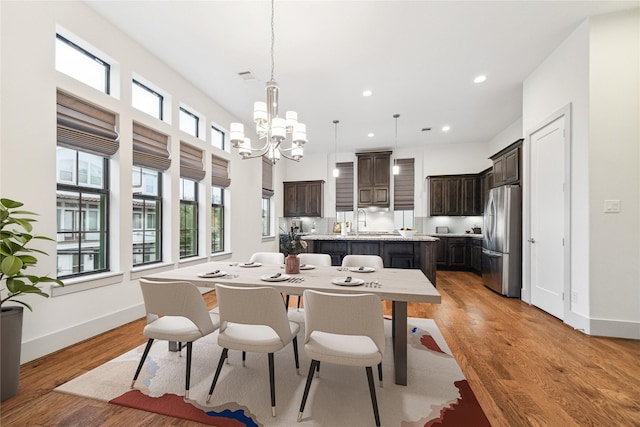 dining space with sink, light hardwood / wood-style flooring, and a chandelier