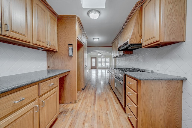 kitchen with dark stone countertops, range with two ovens, ceiling fan, crown molding, and light wood-type flooring