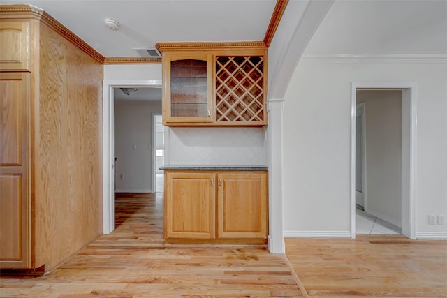 kitchen featuring tasteful backsplash, crown molding, and light hardwood / wood-style flooring