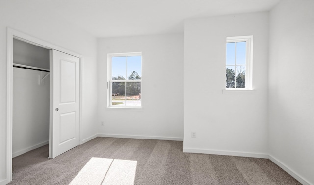 unfurnished bedroom featuring light colored carpet and a closet