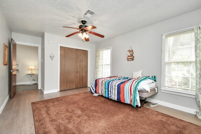 bedroom featuring hardwood / wood-style flooring, a closet, and multiple windows