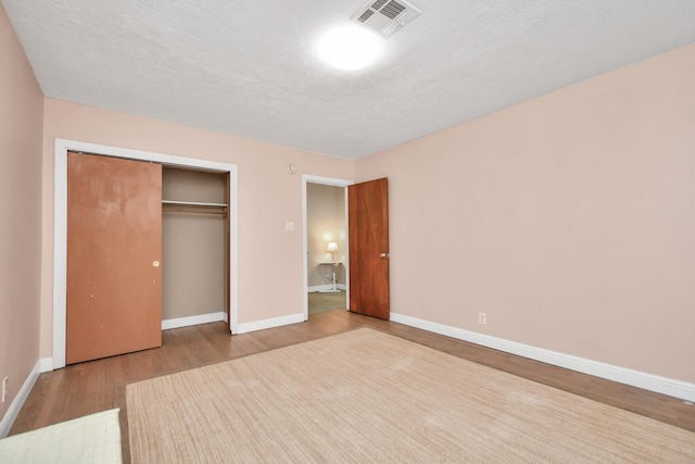 unfurnished bedroom with light hardwood / wood-style floors, a closet, and a textured ceiling