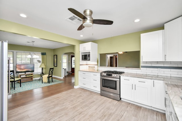 kitchen with appliances with stainless steel finishes, white cabinetry, decorative backsplash, hanging light fixtures, and light stone counters