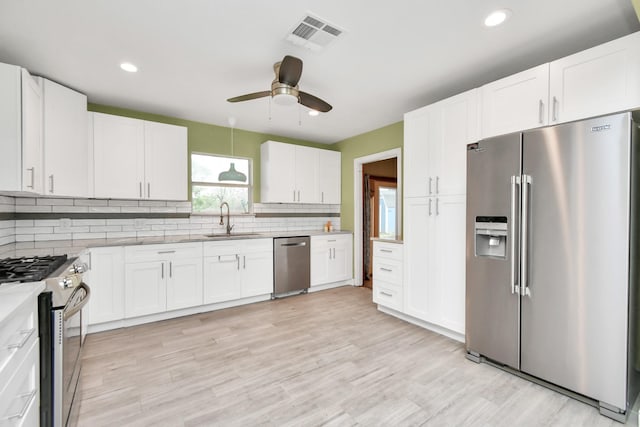 kitchen featuring stainless steel appliances, white cabinetry, sink, and backsplash