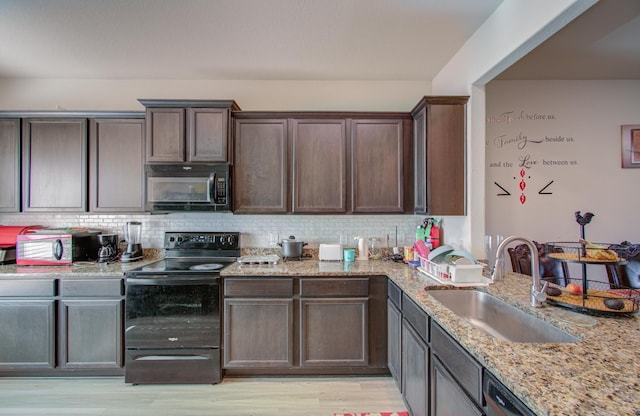 kitchen with sink, tasteful backsplash, light stone counters, dark brown cabinets, and black appliances