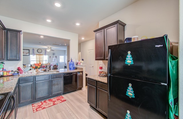 kitchen with dark brown cabinets, light stone counters, light hardwood / wood-style floors, and black appliances