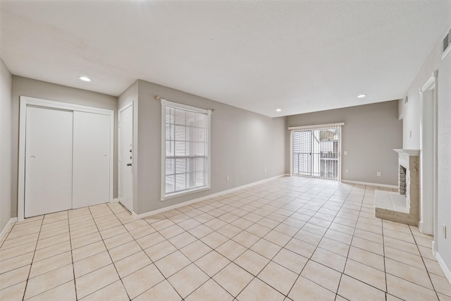 unfurnished living room featuring a brick fireplace and light tile patterned floors