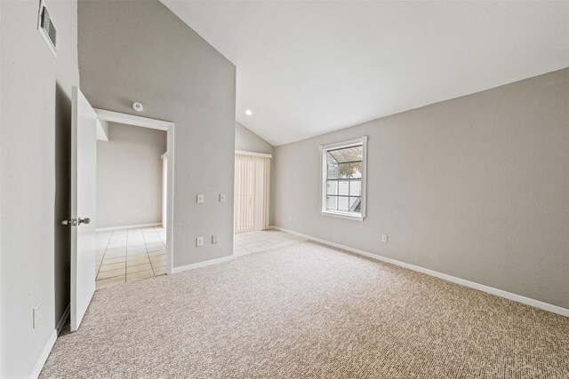 carpeted empty room with vaulted ceiling