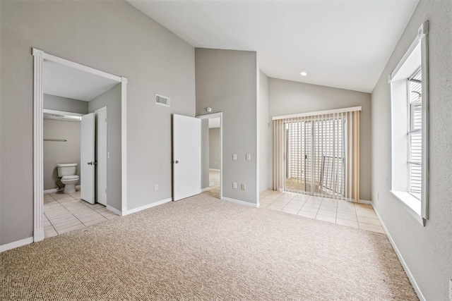 unfurnished bedroom featuring connected bathroom, light colored carpet, and high vaulted ceiling