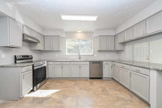 kitchen with light stone counters, sink, gray cabinets, and appliances with stainless steel finishes