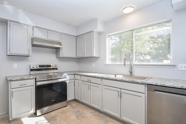 kitchen with light stone countertops, appliances with stainless steel finishes, and sink