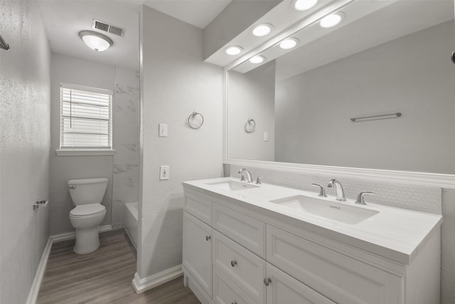 full bathroom with vanity, wood-type flooring, toilet, and washtub / shower combination