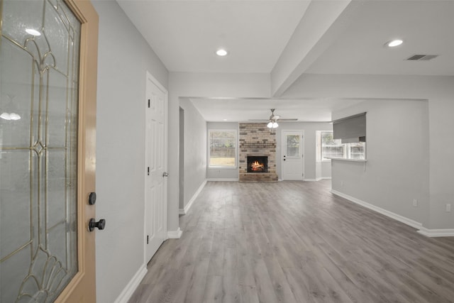 unfurnished living room with wood-type flooring, a brick fireplace, and ceiling fan