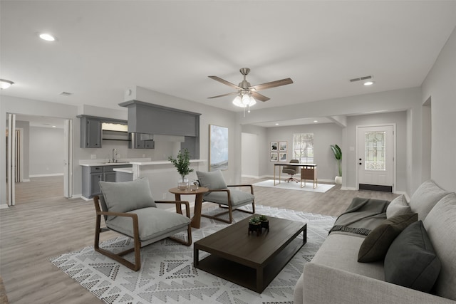 living room featuring sink, light hardwood / wood-style flooring, and ceiling fan