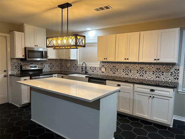 kitchen featuring pendant lighting, appliances with stainless steel finishes, sink, and white cabinets