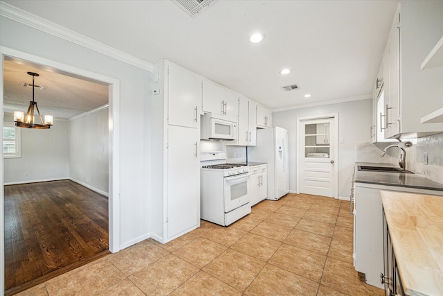 kitchen with pendant lighting, sink, white cabinets, ornamental molding, and white appliances