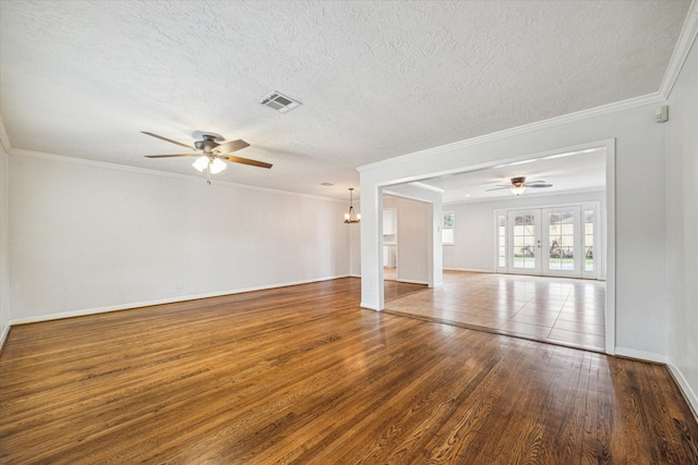 unfurnished living room featuring french doors, ornamental molding, wood-type flooring, and a textured ceiling