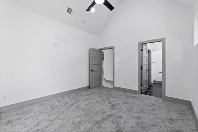 unfurnished bedroom with ceiling fan, ensuite bath, high vaulted ceiling, and dark carpet