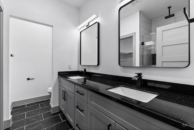 bathroom featuring a shower with door, vanity, and toilet