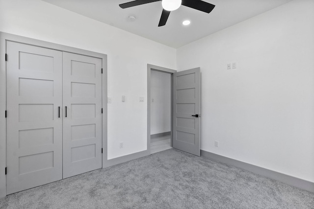 unfurnished bedroom featuring light colored carpet, a closet, and ceiling fan