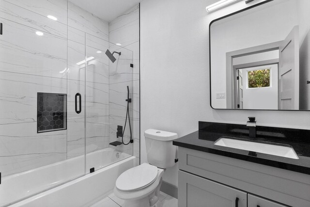 full bathroom with vanity, bath / shower combo with glass door, and toilet