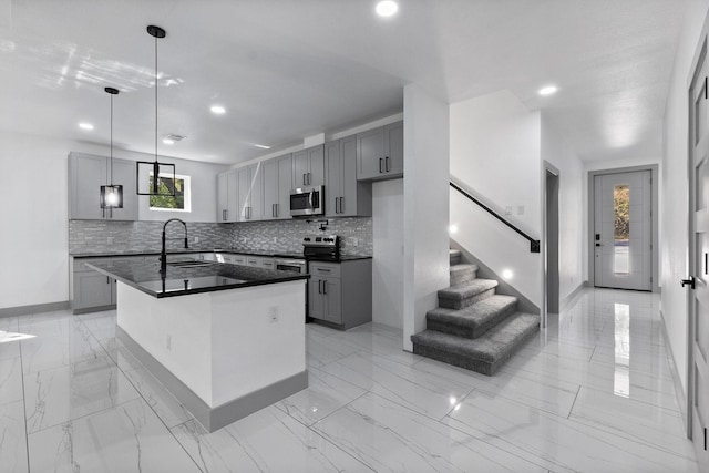 kitchen with gray cabinetry, hanging light fixtures, stainless steel appliances, and a kitchen island