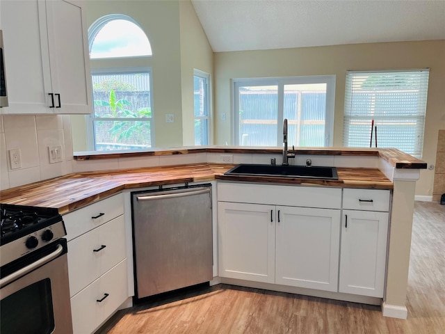 kitchen with stainless steel appliances, wooden counters, sink, and white cabinets