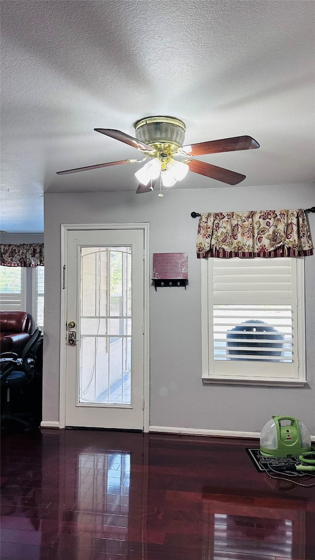 doorway with dark hardwood / wood-style floors, ceiling fan, a healthy amount of sunlight, and a textured ceiling