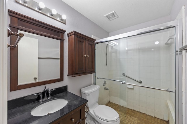 bathroom featuring vanity, toilet, and a shower with shower door