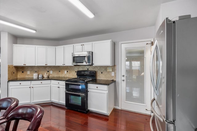 kitchen featuring dark hardwood / wood-style flooring, tasteful backsplash, stainless steel appliances, and white cabinets