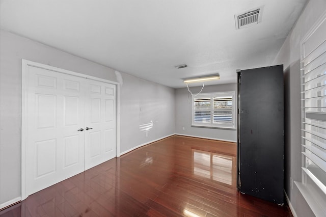 unfurnished bedroom featuring dark hardwood / wood-style flooring and a closet