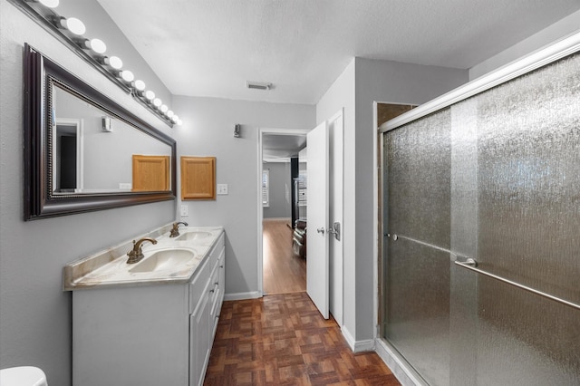 bathroom with vanity, parquet floors, a shower with door, and a textured ceiling