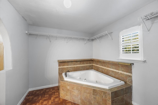 bathroom featuring a relaxing tiled tub and parquet flooring