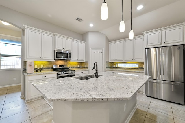 kitchen featuring white cabinetry, stainless steel appliances, and an island with sink