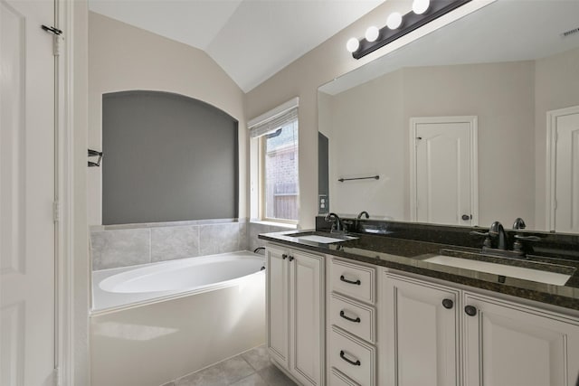 bathroom featuring a tub to relax in, lofted ceiling, vanity, and tile patterned flooring