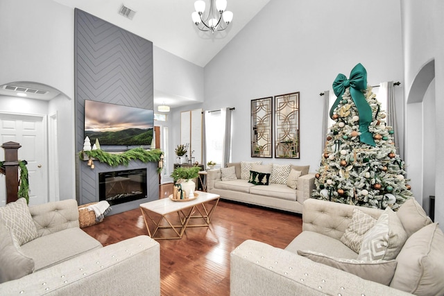 living room featuring dark hardwood / wood-style flooring, a fireplace, high vaulted ceiling, and a chandelier