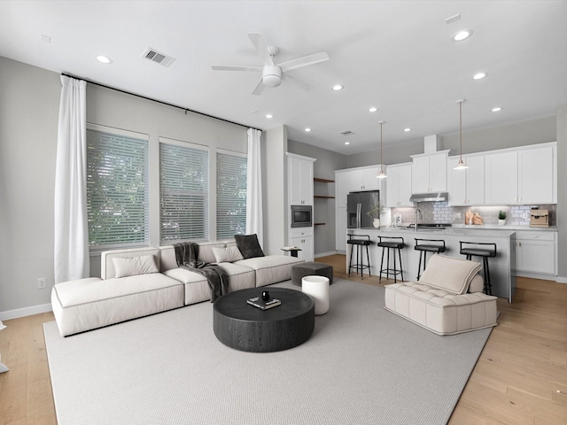 living room with ceiling fan and light wood-type flooring