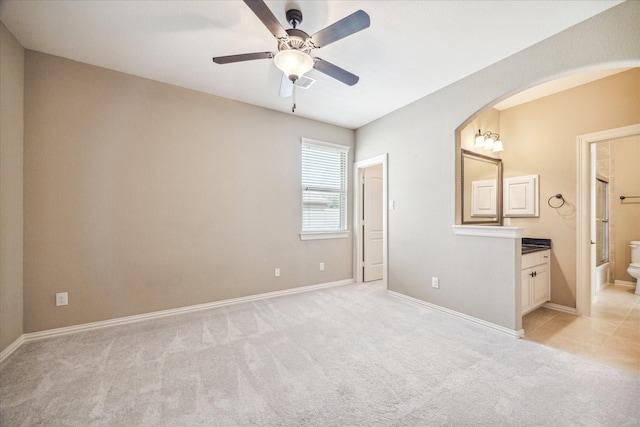 unfurnished bedroom featuring ceiling fan, connected bathroom, and light carpet