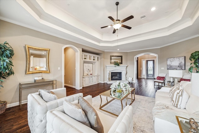 living room with crown molding, ceiling fan, dark hardwood / wood-style flooring, and a tray ceiling