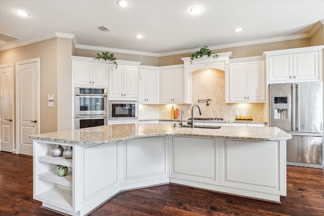 kitchen featuring sink, appliances with stainless steel finishes, white cabinetry, light stone countertops, and an island with sink