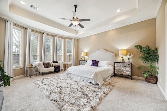 bedroom with crown molding, light carpet, ceiling fan, and a tray ceiling